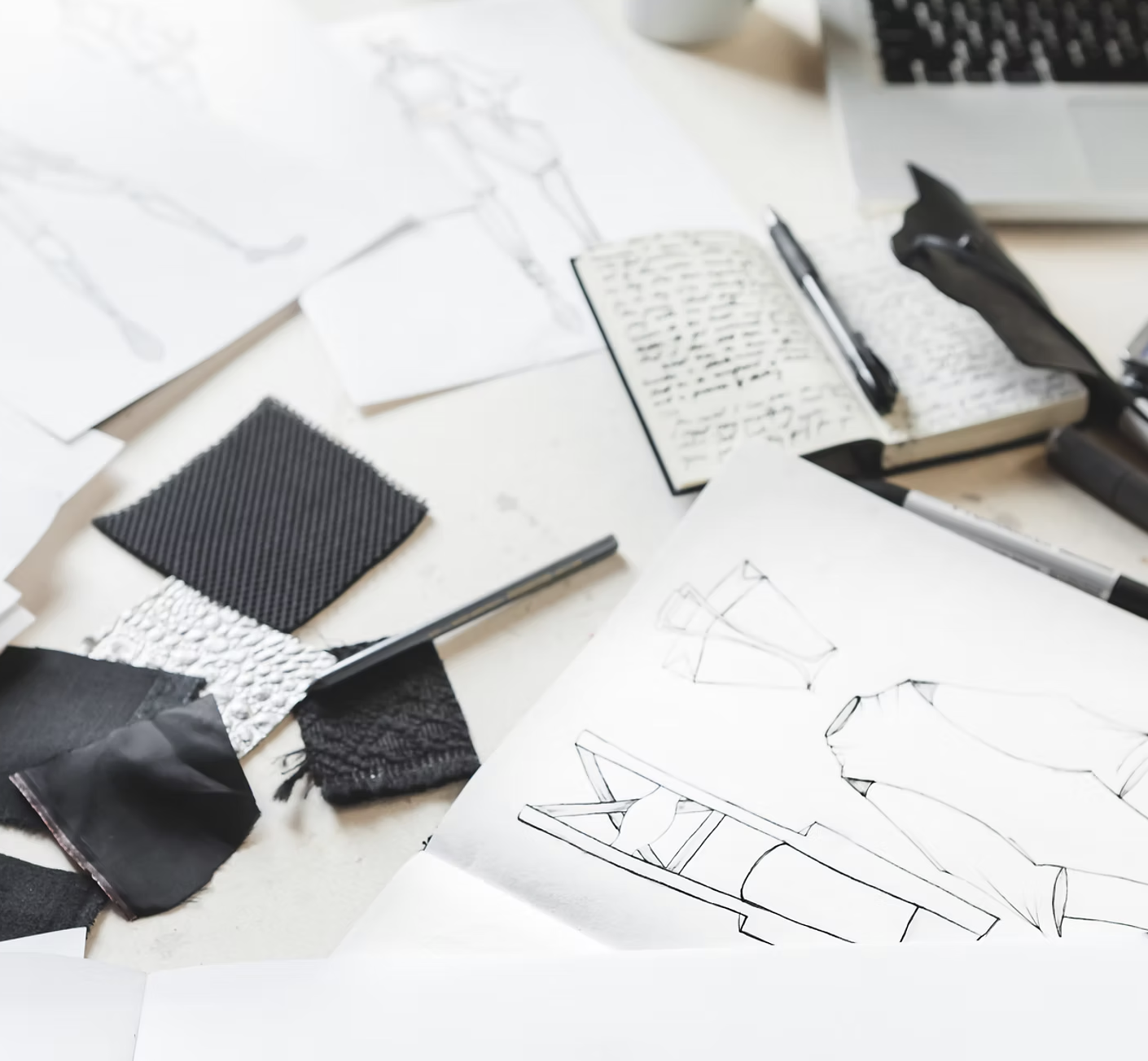Fashion sketches, fabric swatches and technical drawings on a design desk
